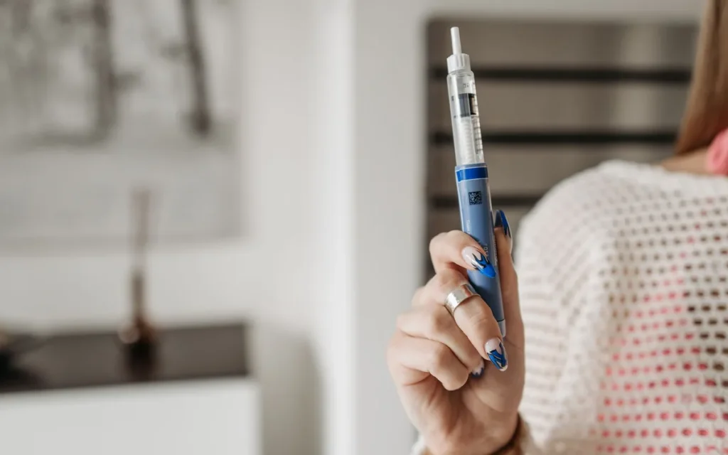 Person holding a weekly injection pen, representing a tirzepatide dosing schedule